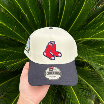 Gorra New Era 9FORTY ajustable con logo de medias rojas frente a planta verde
